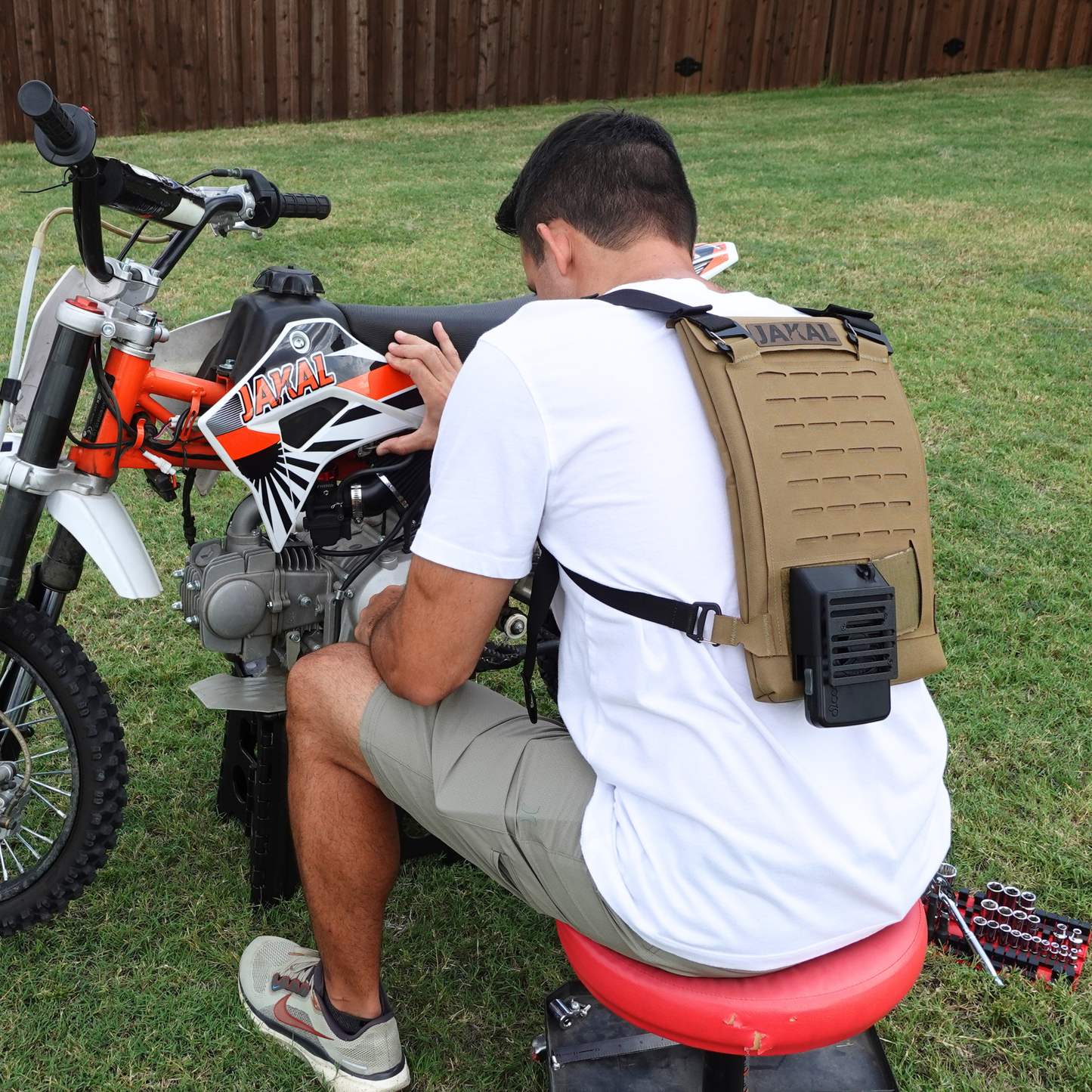 man wearing a cooling backpack while working on a dirtbike. 